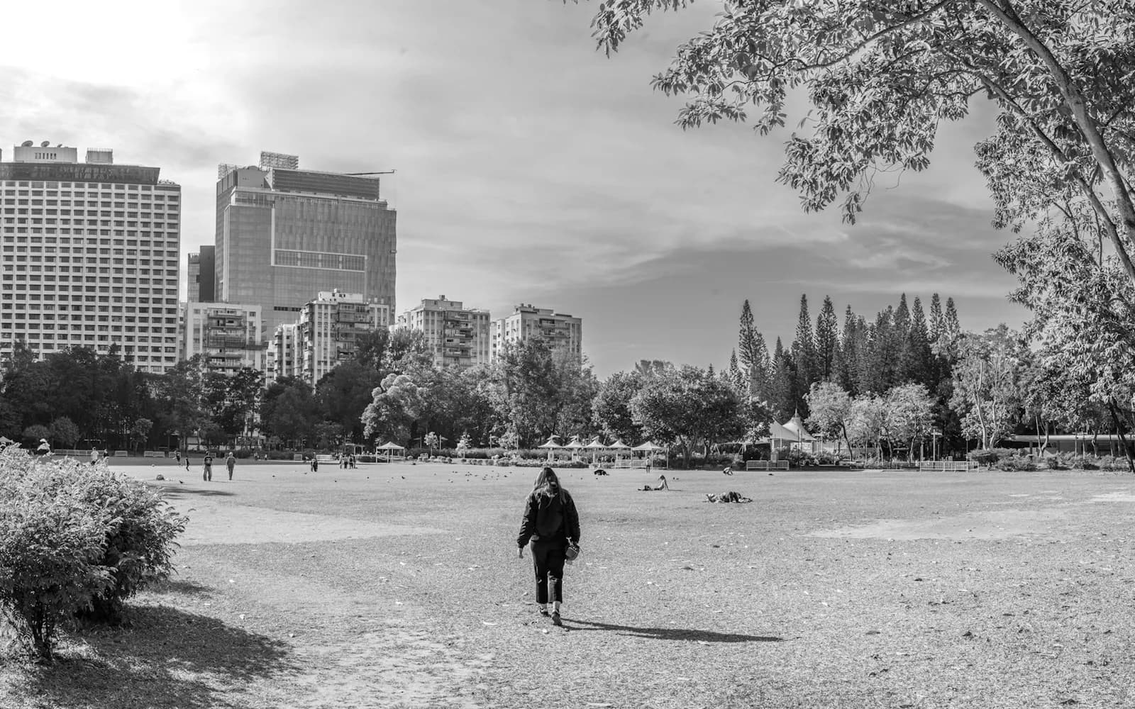 Personne qui marche seule dans un parc, avec les tours du centre-ville en arrière-plan